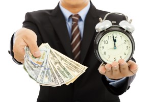 Businessman Holding Money And Clock. Time Is Money Concept