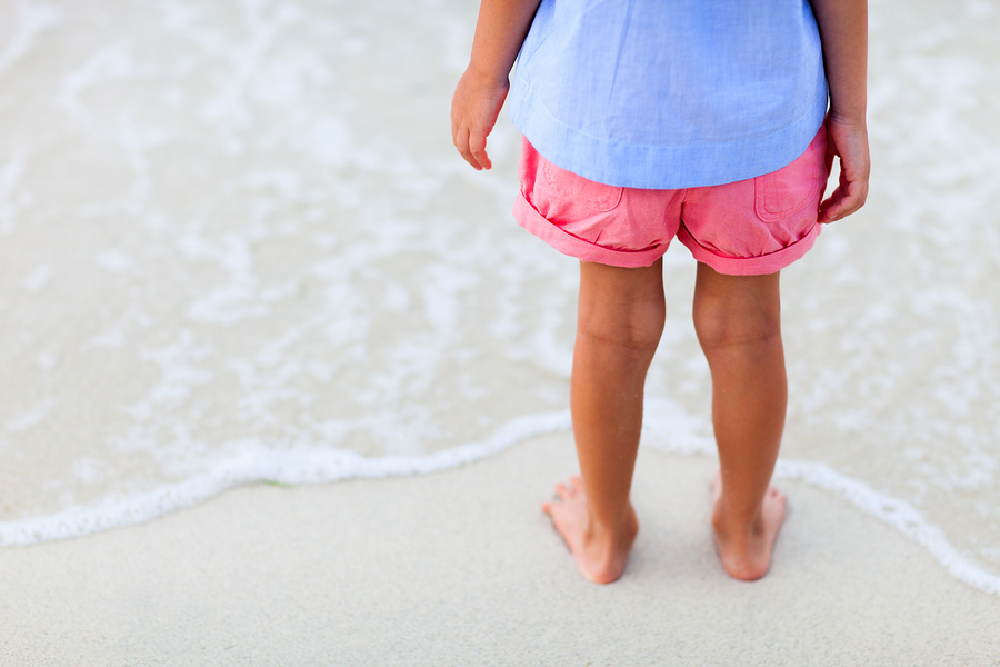 Close up of a little girl feet on tropical sandy beach