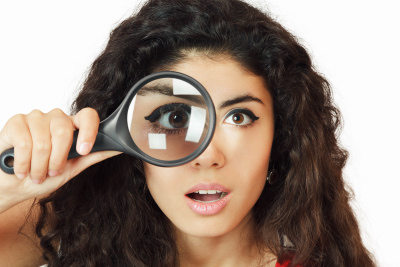 Surprised girl looking through magnifying glass